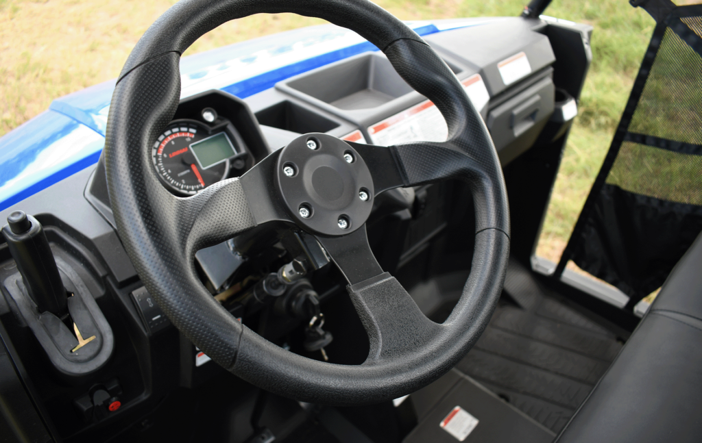 Close-up view of a UTV's steering wheel and dashboard controls.