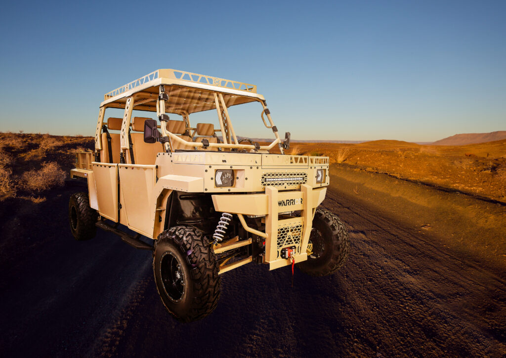 A Massimo Warrior MXD Crew utility vehicle on a rugged desert trail at sunset.